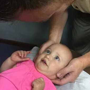 Dr. Adcock adjusting an infant.